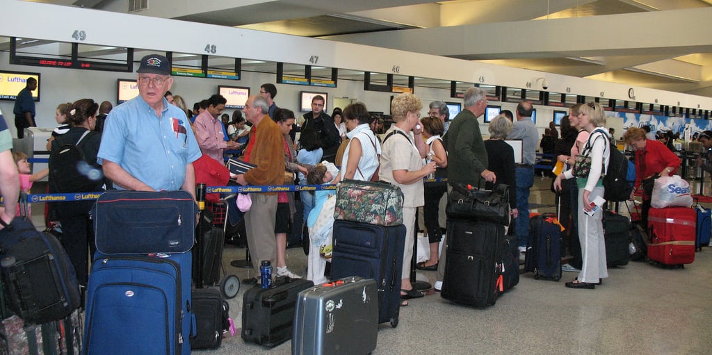 Check in line at airport with many passengers and their luggage