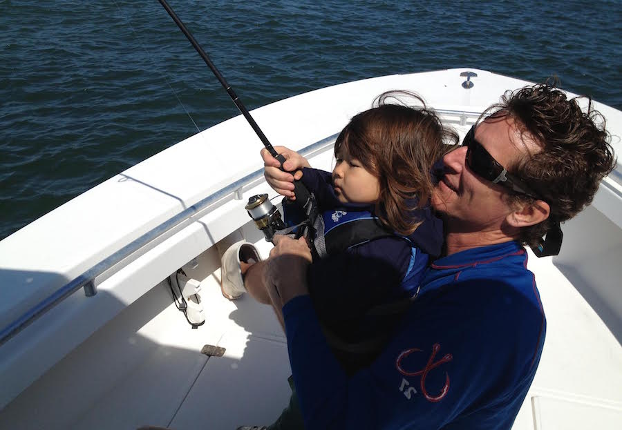 Father and son fishing, dad is helping his kid land a fish