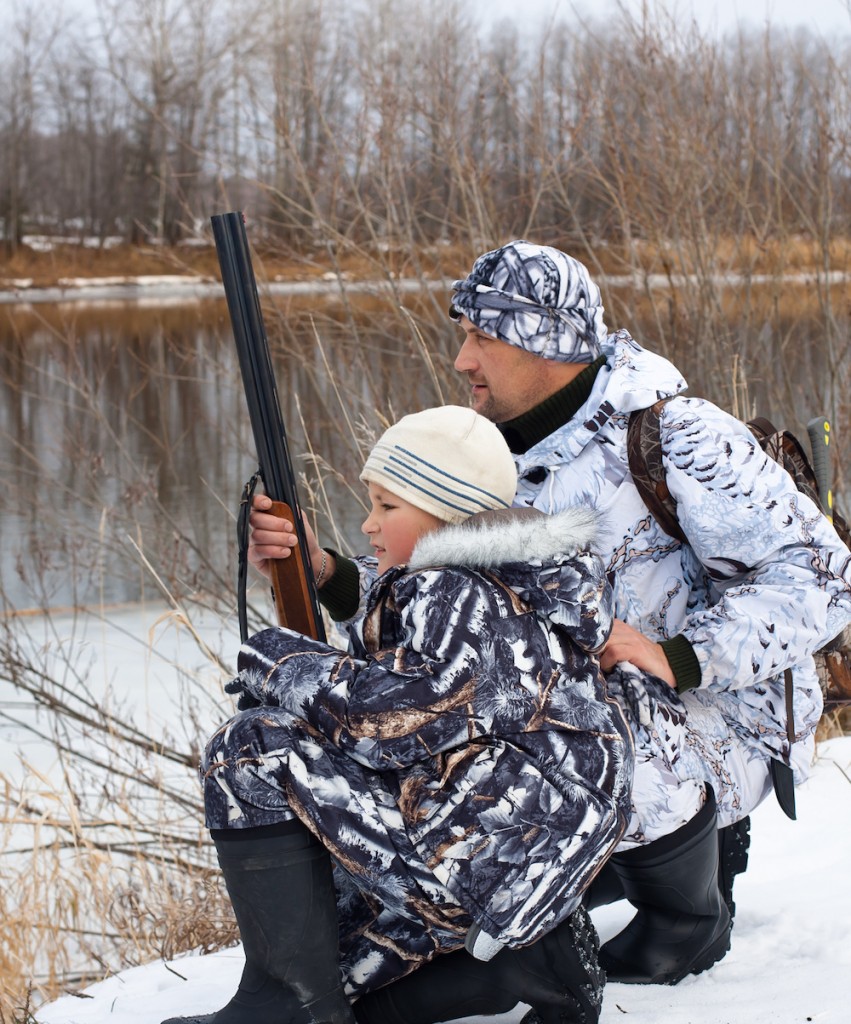 hunter with his son on the riverbank during winter hunting